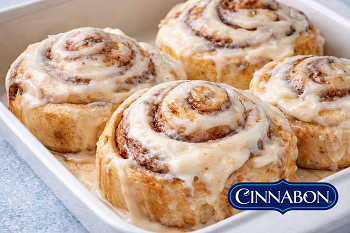 Soft cinnamon rolls with cream cheese frosting served warm in a baking dish"