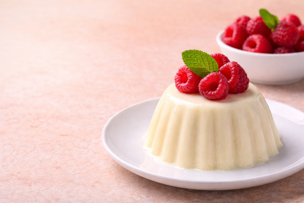 Keto panna cotta topped with fresh raspberries and mint on a white plate