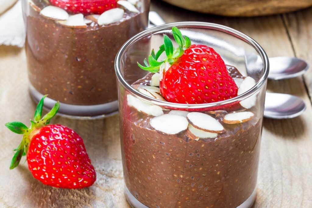 Healthy chocolate chia pudding made with chia seeds, topped with fresh strawberries and almonds in glass cups